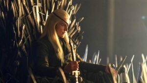 Cosplayer with Long Blonde Hair Sits on the Iron Throne a Throne Carved from Swords in a Dimly Lit Scene