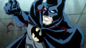 Batman in a Blue Suit Lunges Forward with His Cape Billowing Blood Splatters on His Face and Costume in an Intense Action Scene