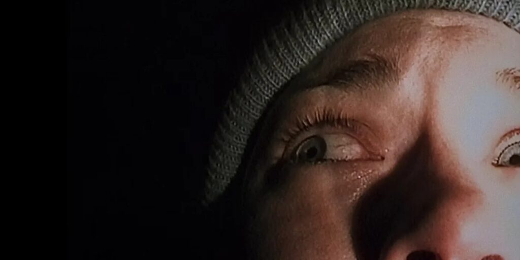 Close up of a Persons Scared Face Wide Eyes Looking Upward Wearing a Gray Knit Beanie with a Dark Background