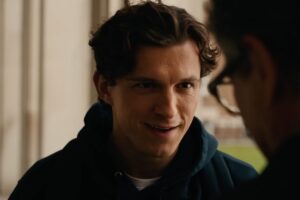 Close up of a Young Man in a Dark Hoodie Smiling During a Conversation with Someone Off camera