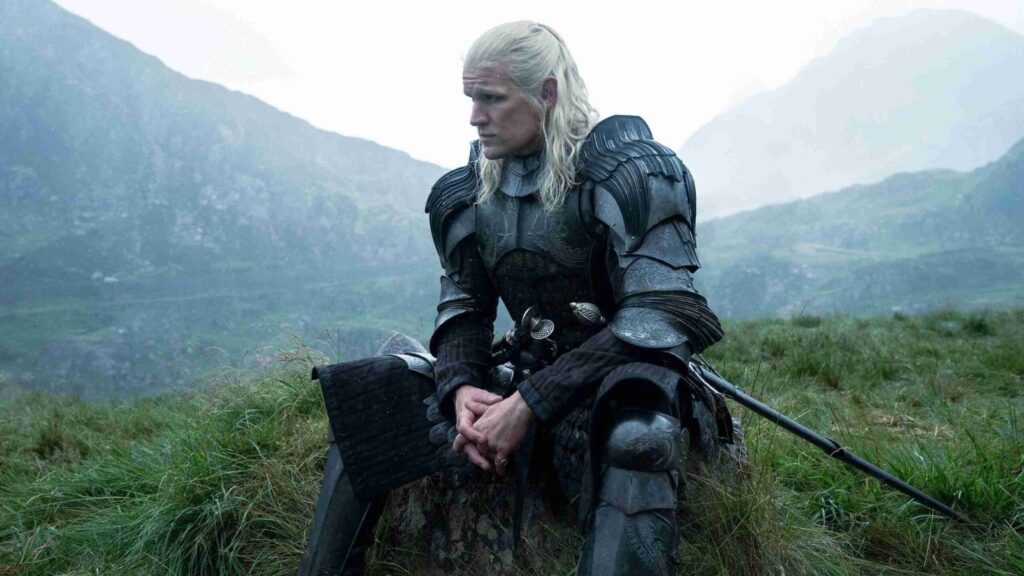 Knight in Dark Ornate Armor Sitting in a Grassy Field with Misty Mountains in the Background