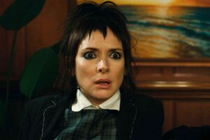 Woman with Short Black Hair and Dramatic Makeup Wearing a Suit Looks Surprised Indoors