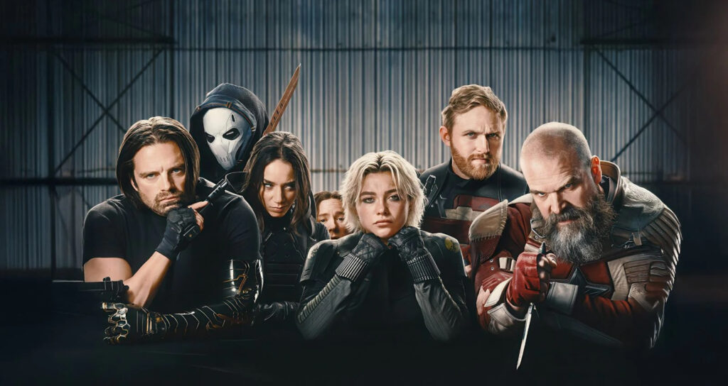 Six Costumed Superheroes Posing Behind a Dark Table in a Dim Industrial Warehouse Some with Weapons Visible Facing the Camera