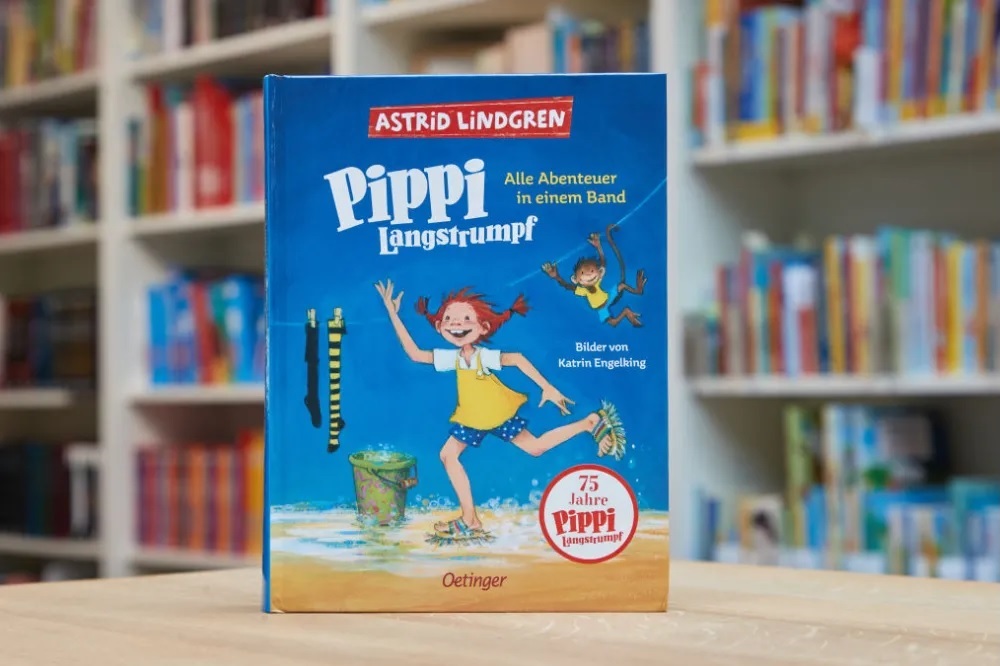 Blue Pippi Longstocking Book on a Wooden Table in a Library Showing Illustrations of a Girl Jumping