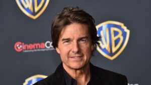 Head and shoulders Portrait of a Man in a Black Suit at a Media Event with a Large Warner Bros Backdrop Logo Behind Him