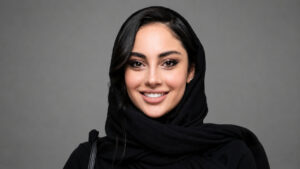 Smiling Woman in a Black Hijab Against a Gray Backdrop Facing the Camera