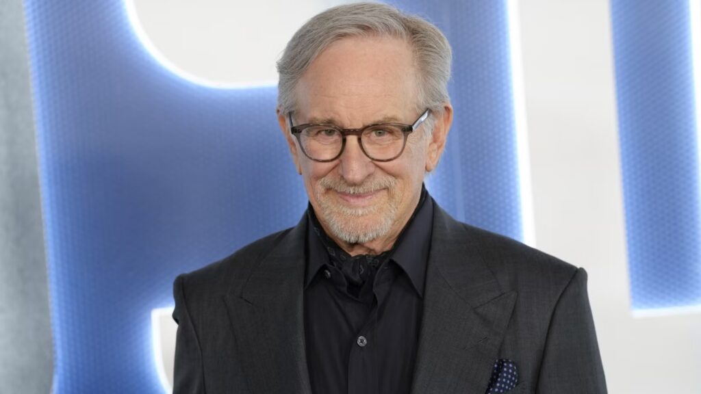 Mature Man with Gray Hair and Glasses in a Dark Suit Smiling at the Camera