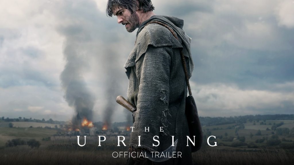 Poster for the Uprising a Man in a Torn Cloak Stands in a Field As Smoke and Fire Rise Behind Him