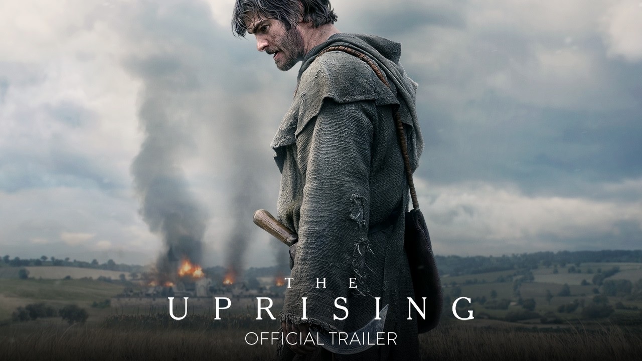 Poster for the Uprising a Man in a Torn Cloak Stands in a Field As Smoke and Fire Rise Behind Him