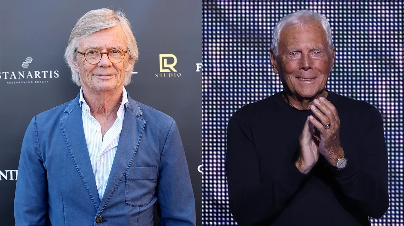 Two Older Men at an Event Left Man with Gray Hair and Glasses in a Blue Blazer Right Man in a Black Shirt Clapping on a Stage Backdrop