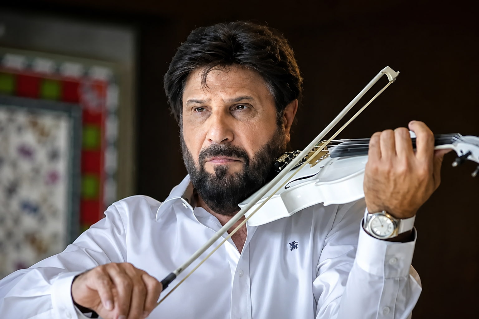 Bearded Man in a White Shirt Plays a White Violin Bow Drawn Across Strings and Focused Expression