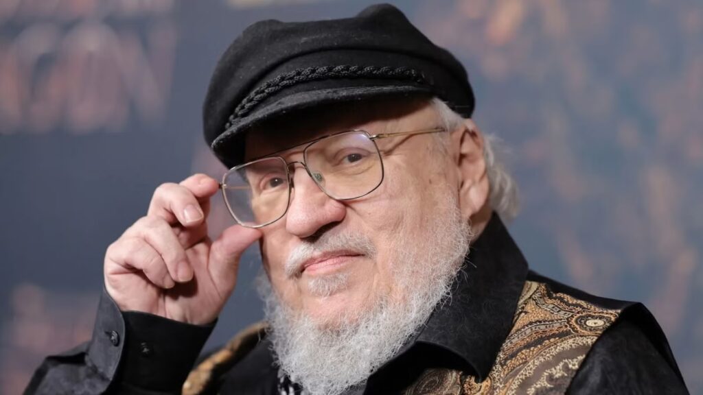 Close up Portrait of an Elderly Man with a White Beard and Glasses Adjusting His Round Eyeglasses While Wearing a Black Cap and a Patterned Vest