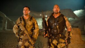 Two Soldiers in Desert Camouflage Tactical Gear Stand at Night Each Holding a Rifle