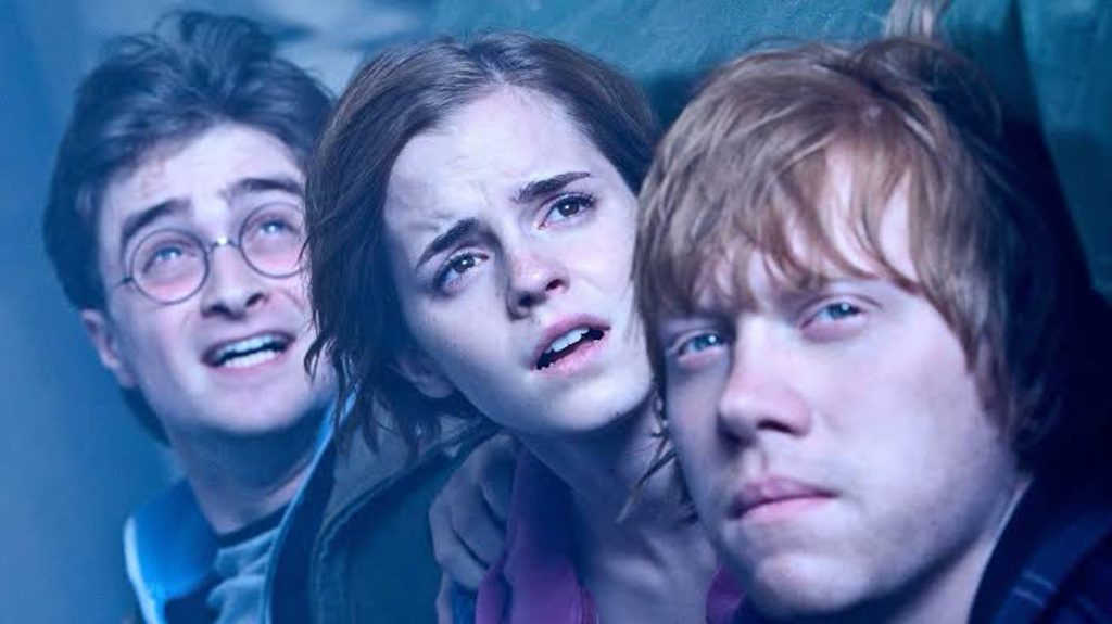 Three Young People Glance Upward with Worried Expressions Huddled Together in a Blue tinted Scene
