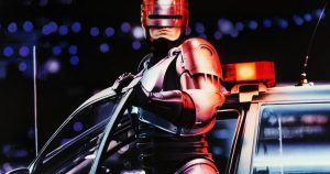 Silver Armored Robot Like a Futuristic Police Officer Leaning from a Patrol Car with Red Siren Light in the Background at Night Bokeh Lights Behind It