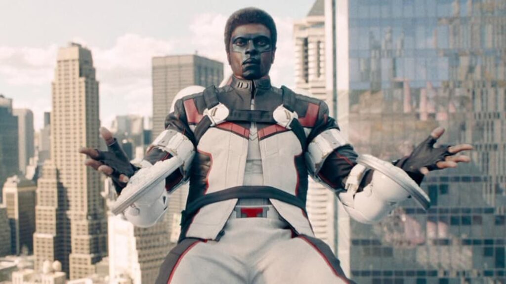 Man in a White and Red High tech Armor Suit Stands on a City Rooftop with Arms Spread Wide