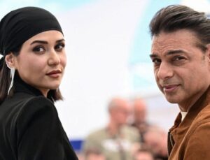 Woman in a Black Headscarf and a Man in a Brown Jacket Turn Toward the Camera in a Bright Outdoor Setting Both Looking Back over Their Shoulders