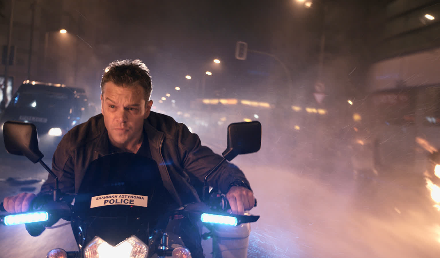 a Police Officer Rides a Motorcycle at Night Through a Hazy Smoke filled Street with Blue Headlights