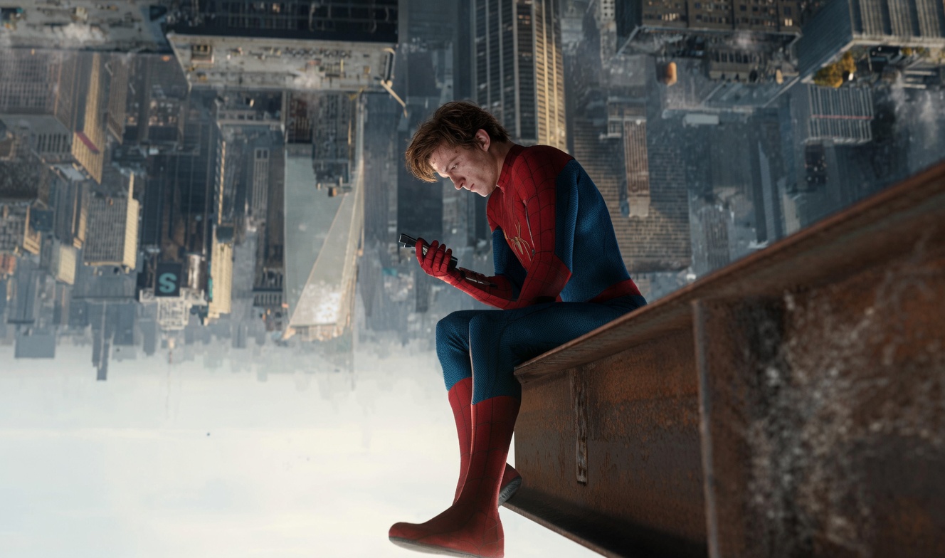 Spider man in His Suit Sits on a Rusted Rooftop Beam Above a City Looking at a Handheld Device