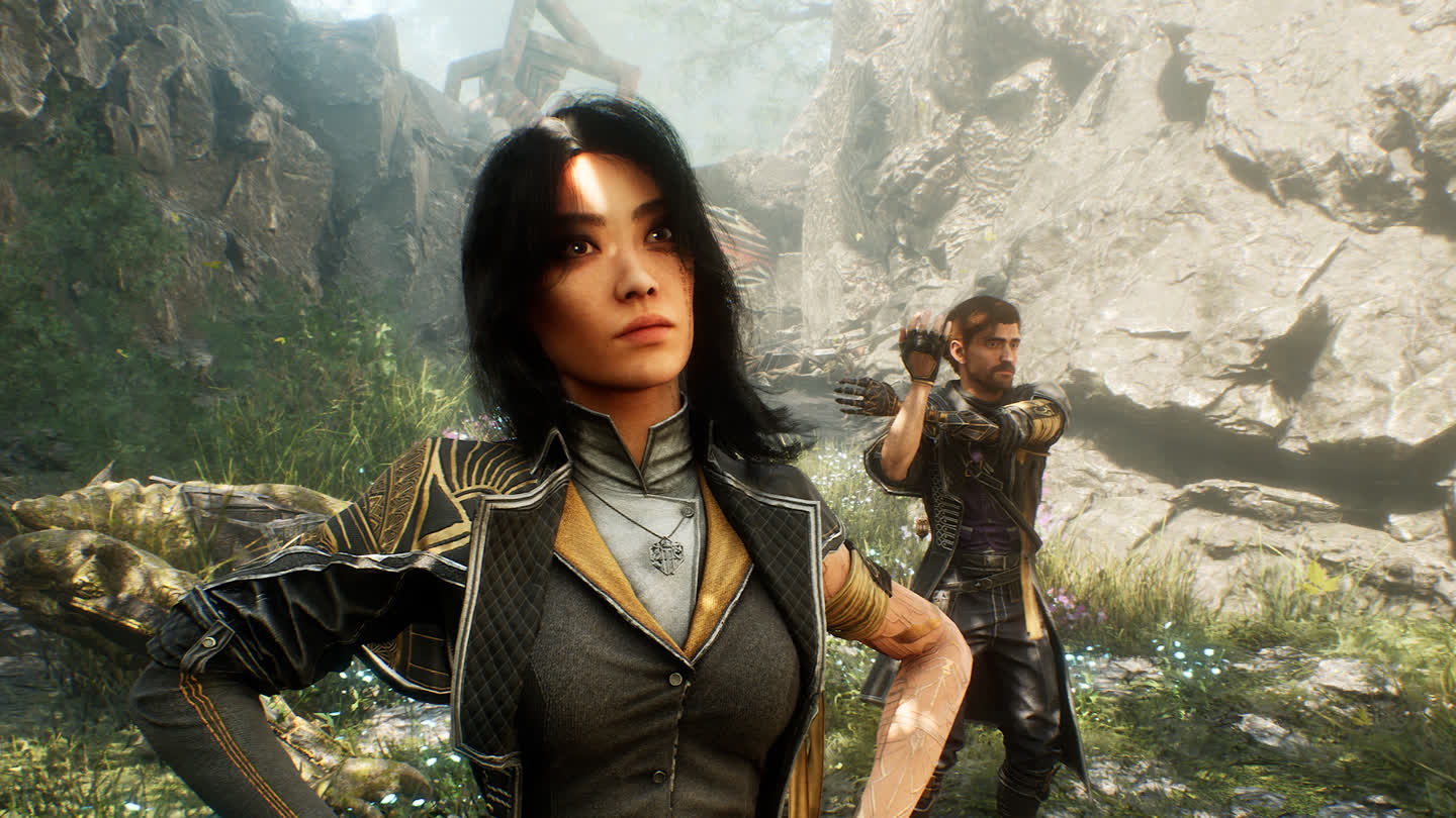 a Female Warrior in Detailed Armor Stands in the Foreground with a Rocky Canyon and Overgrown Plants Behind Her While a Bearded Male Fighter Raises His Arms in the Background