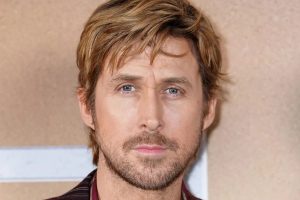 Close up Portrait of a Man with Blond Hair Blue Eyes and Light Stubble Looking at the Camera on a Beige Background