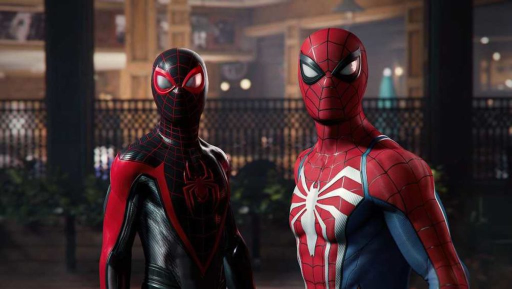 Two Spider man Characters in Full Suits Stand Side by Side in a Dim Indoor Setting