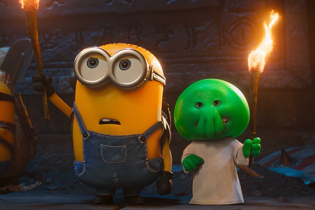 Two Animated Charactersone Yellow Minion in Overalls and a Green Round headed Friendstand in a Dark Cave Each Holding a Lit Torch