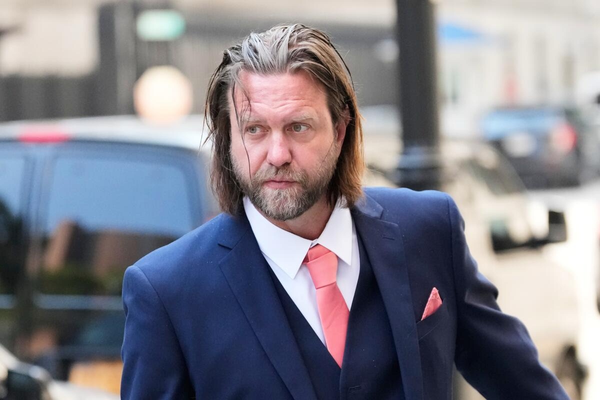 Man in a Navy Suit with a Coral Tie and Pocket Square on a City Sidewalk Looking to the Side